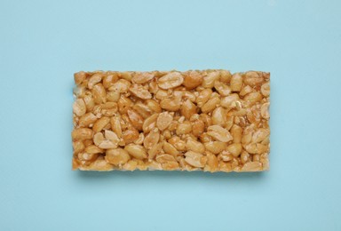 Photo of Tasty peanut bar (kozinaki) on light blue background, top view