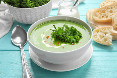 Photo of Tasty kale soup served on light blue wooden table