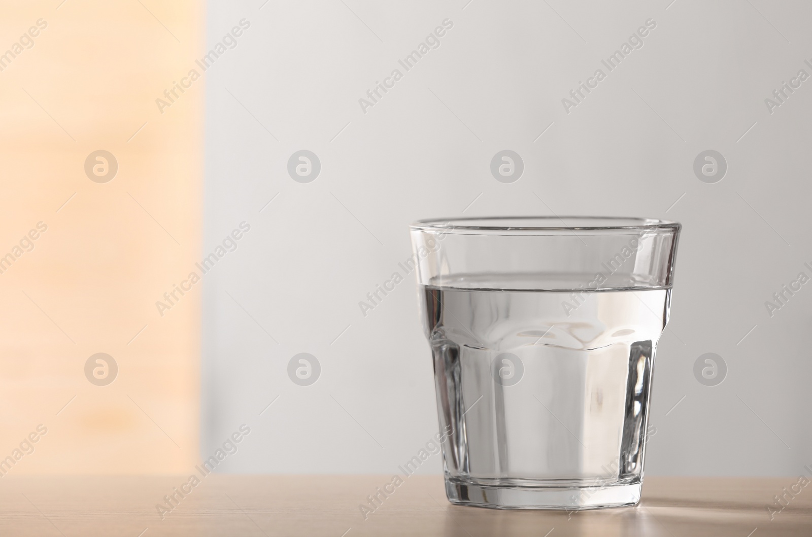 Photo of Glass of pure water on table against blurred background, space for text