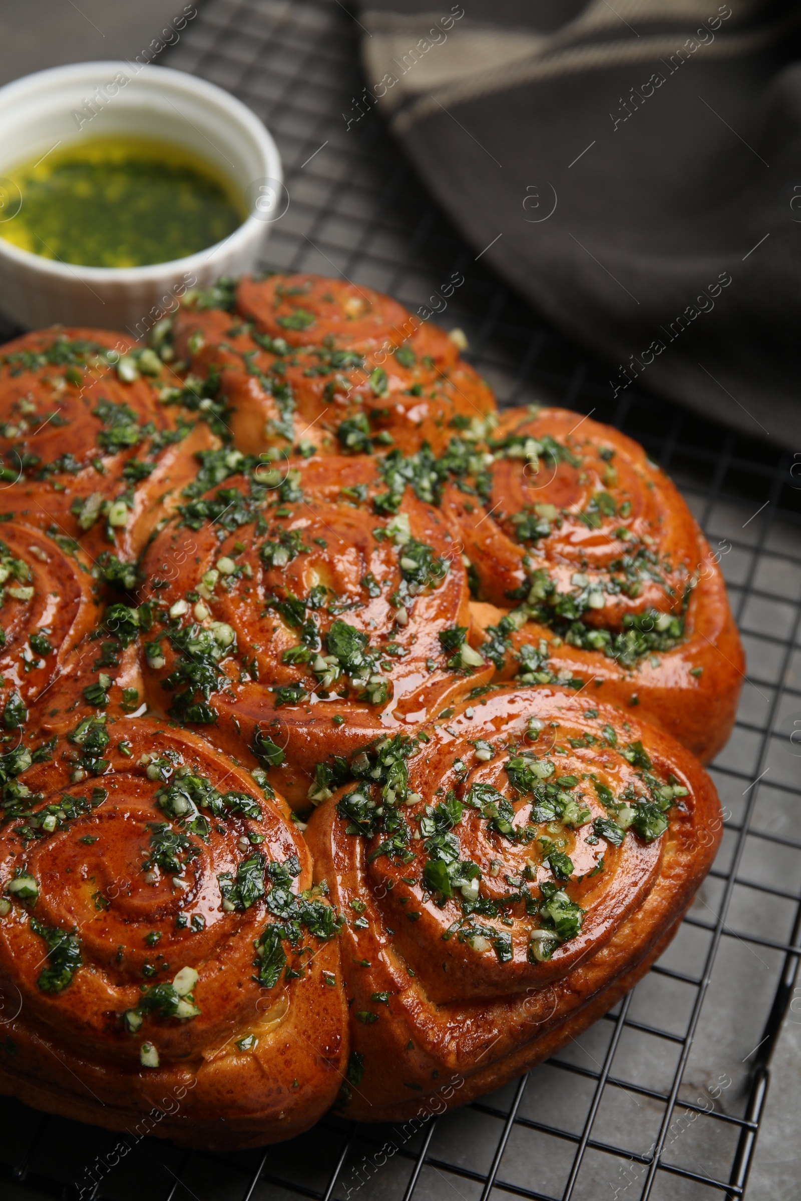 Photo of Traditional Ukrainian garlic bread with herbs (Pampushky) and aromatic oil on grey table, closeup