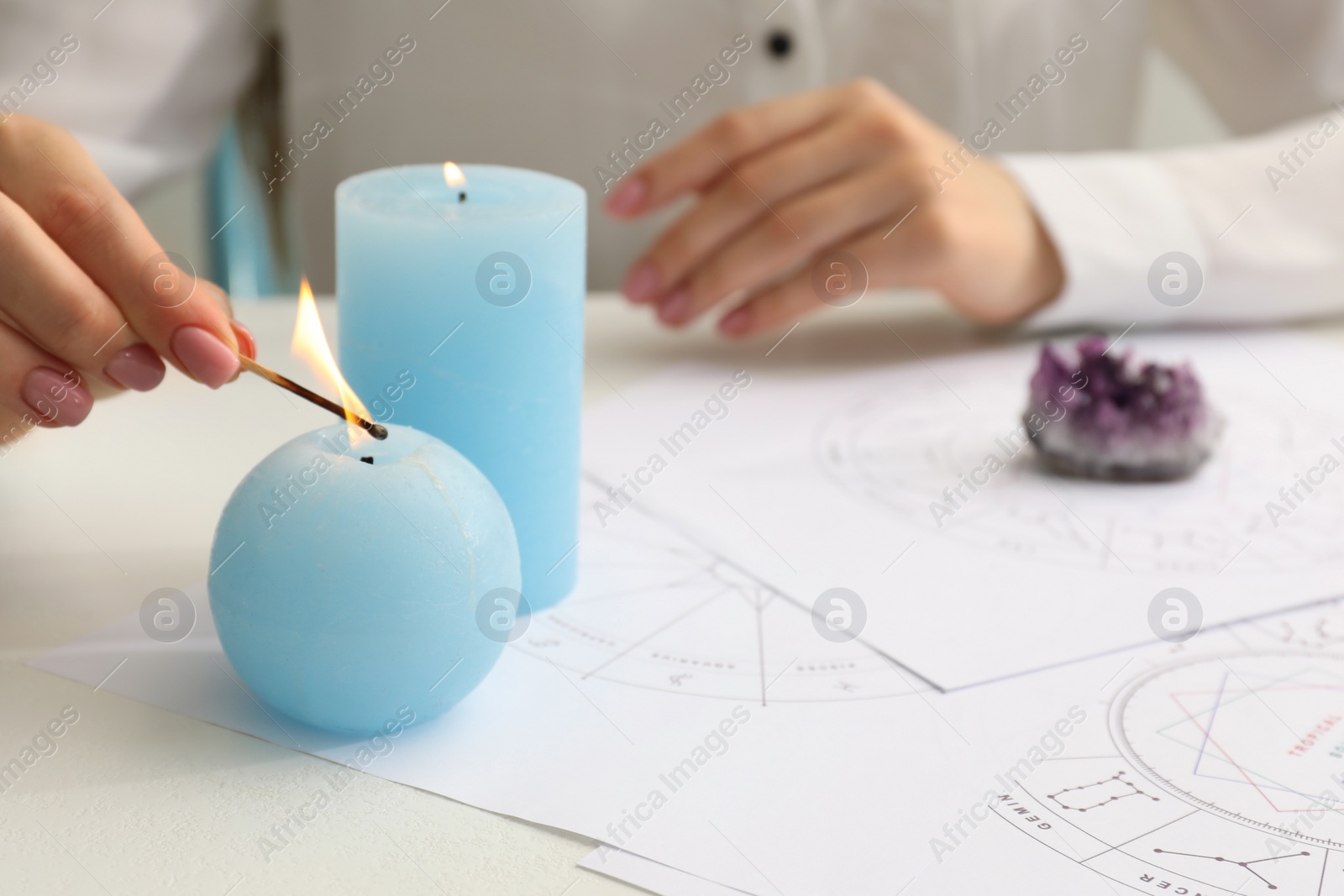 Photo of Astrologer lighting candles at table, closeup. Fortune telling