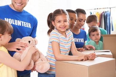 Volunteers with children sorting donation goods indoors