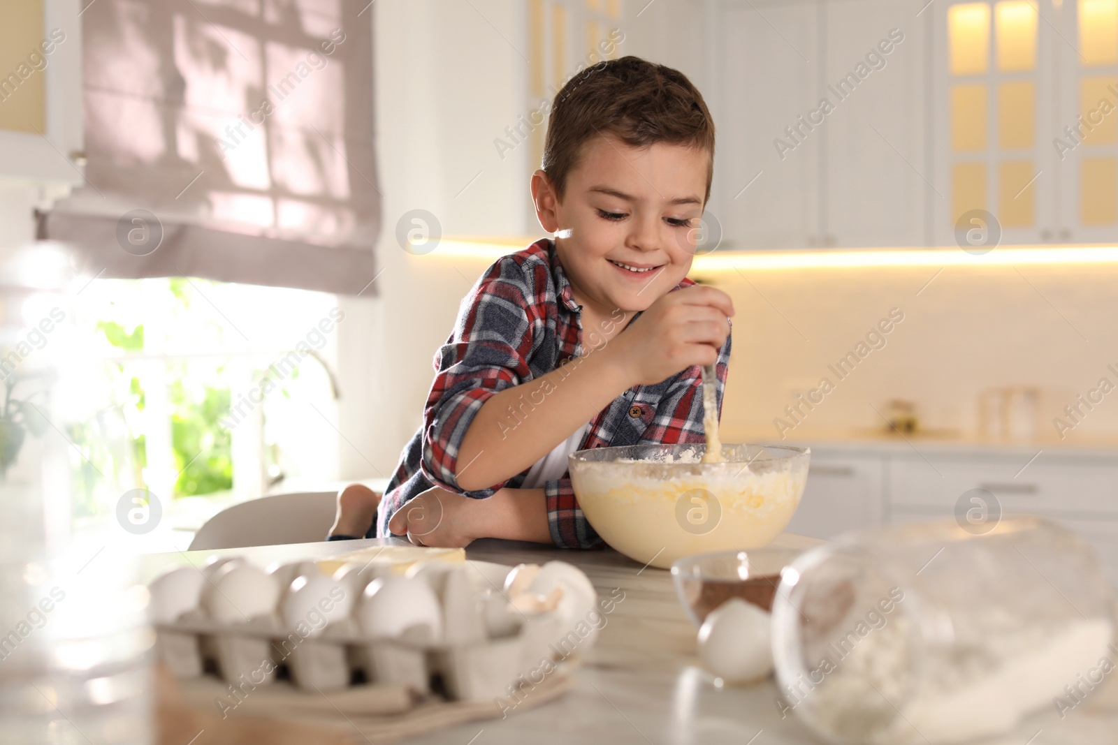 Photo of Cute little boy cooking dough in kitchen at home