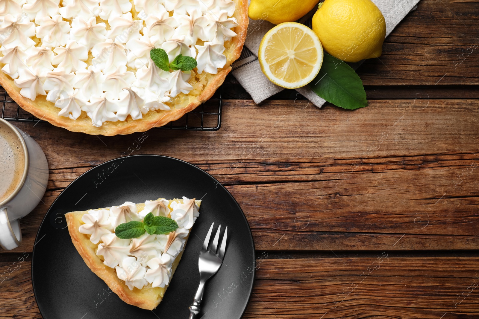 Photo of Cut delicious lemon meringue pie served on wooden table, flat lay. Space for text