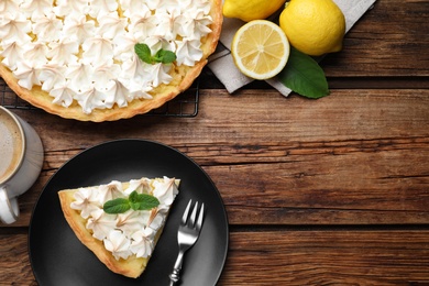 Cut delicious lemon meringue pie served on wooden table, flat lay. Space for text