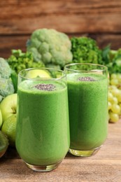 Photo of Glasses of fresh green smoothie on wooden table