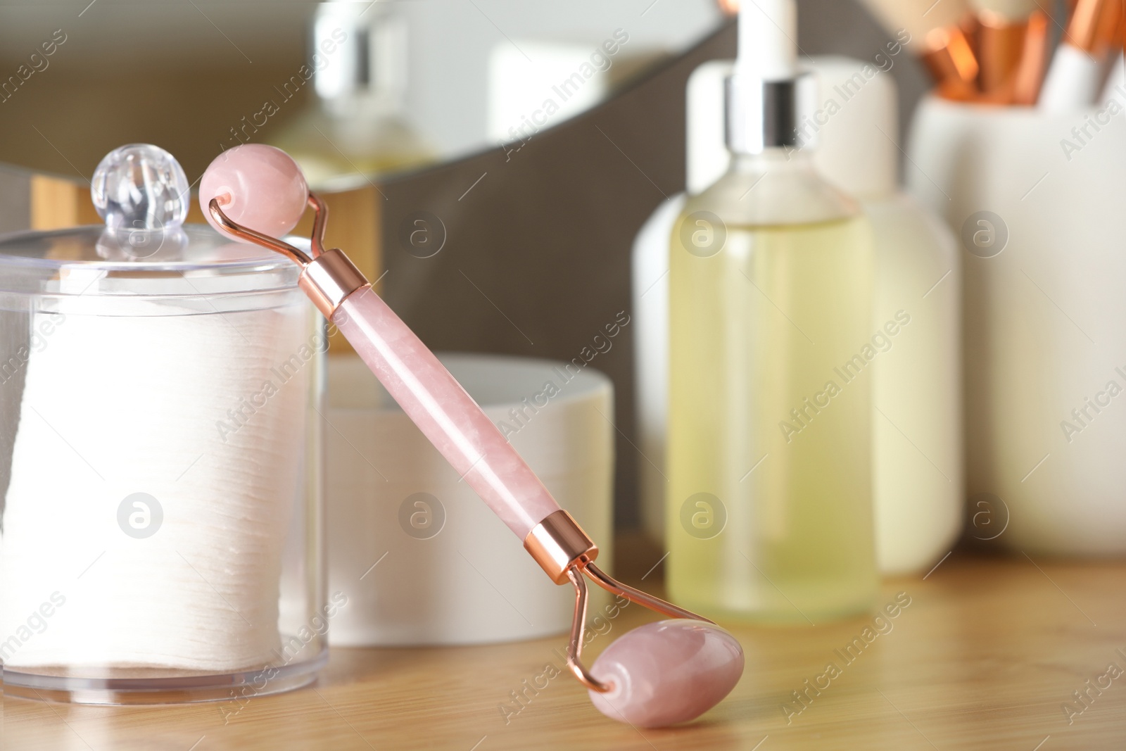 Photo of Natural face roller and cosmetic products on wooden table, closeup