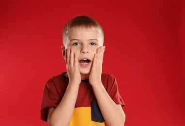 Photo of Portrait of surprised little boy on red background