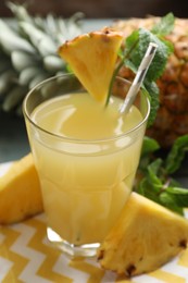 Photo of Delicious pineapple juice in glass and fresh fruit on table, closeup