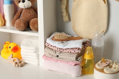 Photo of Baby clothes, toys and accessories on white rack