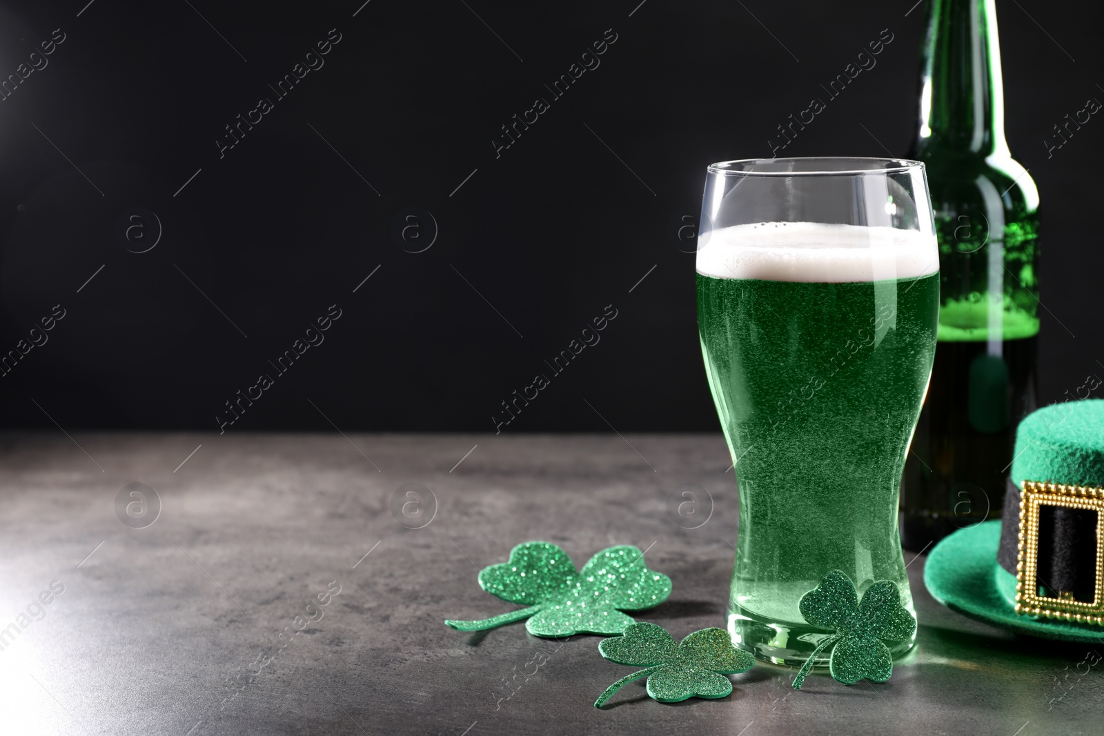 Photo of St. Patrick's day celebration. Green beer, leprechaun hat and decorative clover leaves on grey table. Space for text