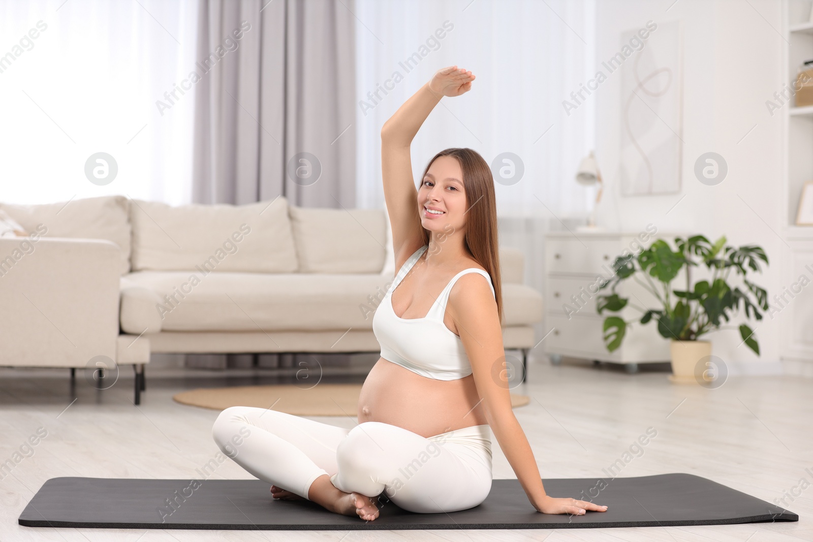 Photo of Pregnant woman doing exercises on yoga mat at home