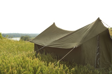 Camping tent in green field on sunny day. Space for text