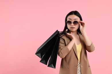 Beautiful woman with shopping bags on pink background. Space for text