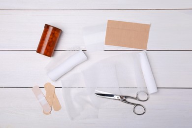 Photo of Bandage rolls and medical supplies on white wooden table, flat lay
