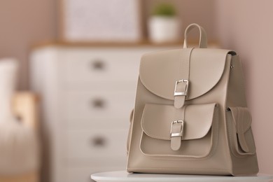 Stylish beige backpack on white table indoors, space for text