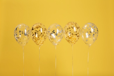 Bright balloons with ribbons on color background