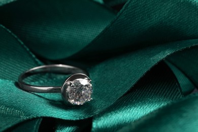 Beautiful luxury engagement ring with gemstone on green ribbon, closeup