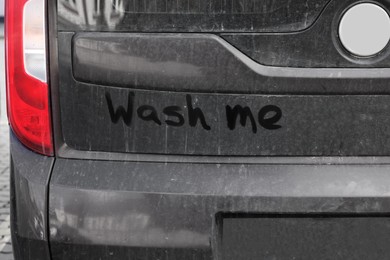 Inscription WASH ME on dirty car, closeup