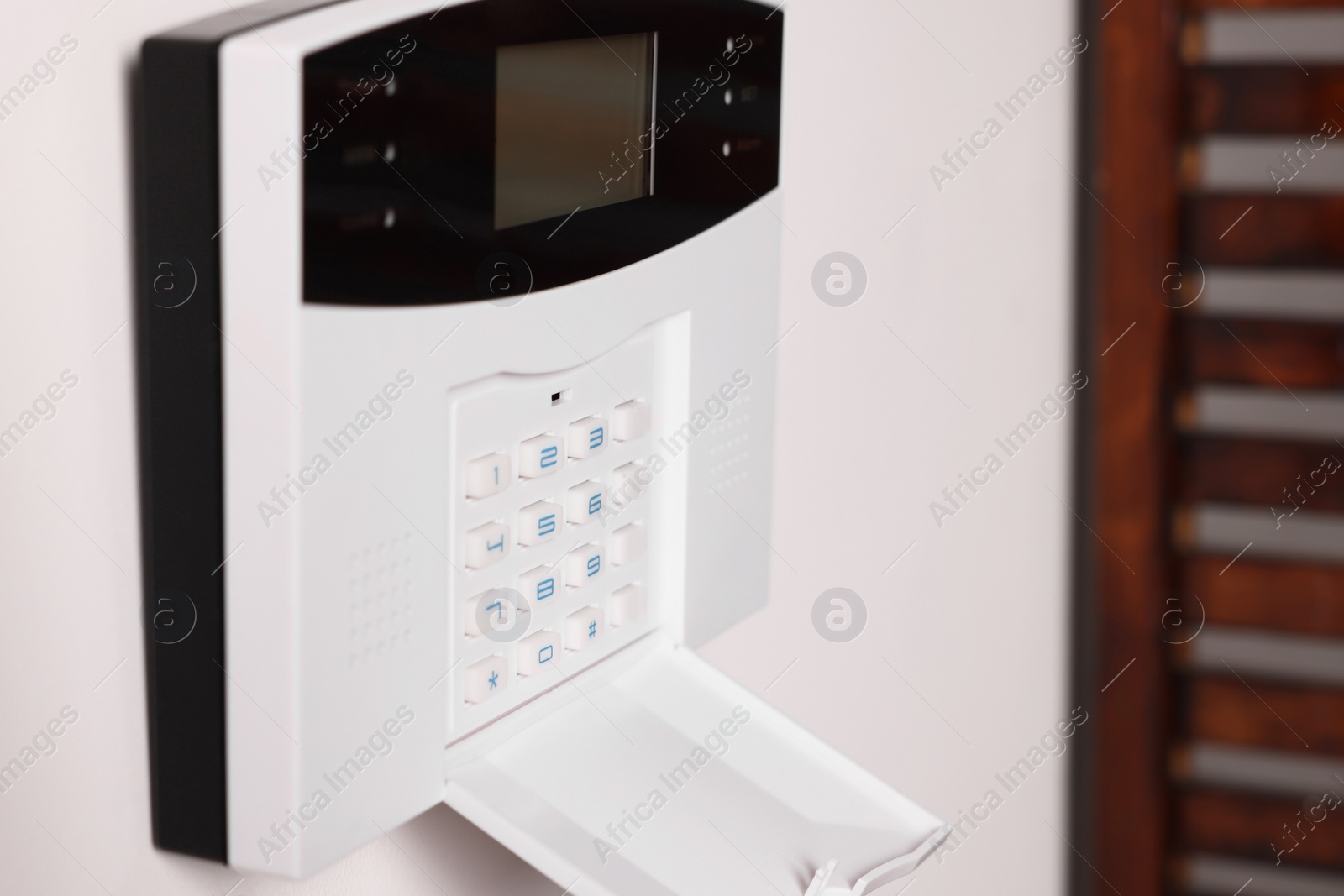 Photo of Home security alarm system on white wall indoors, closeup. Space for text