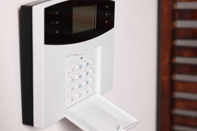 Home security alarm system on white wall indoors, closeup. Space for text