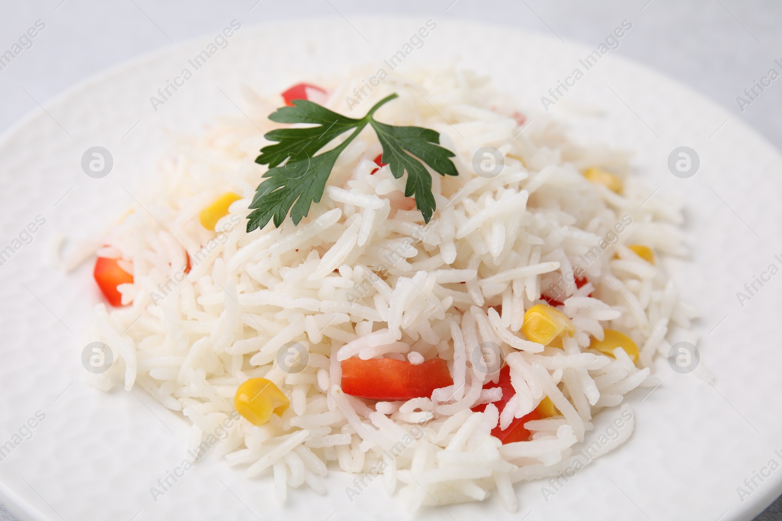 Photo of Plate of delicious rice with vegetables and parsley, closeup