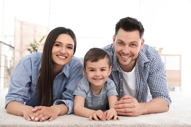 Photo of Happy couple and their son lying on carpet at home. Family time