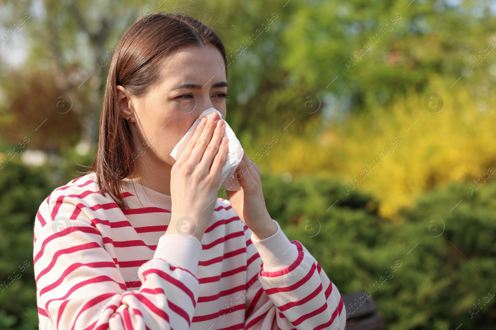 Photo of Woman with napkin suffering from seasonal allergy outdoors