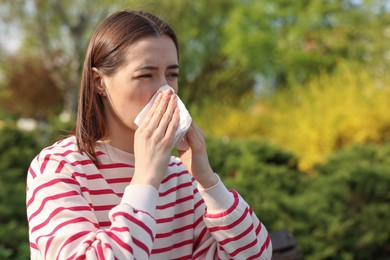 Woman with napkin suffering from seasonal allergy outdoors