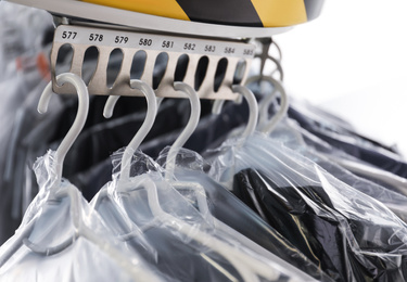 Photo of Hangers with clothes on garment conveyor at dry-cleaner's, closeup