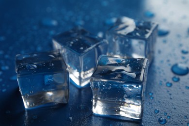 Photo of Ice cubes with water drops on blue background, closeup