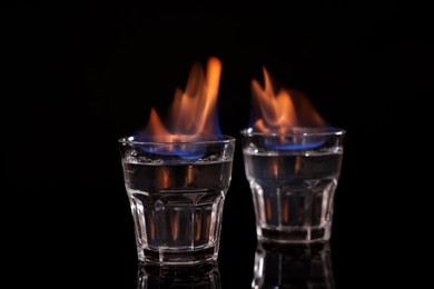 Photo of Flaming vodka in shot glasses on black background