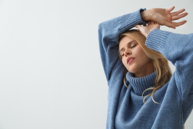 Photo of Beautiful young woman wearing warm blue sweater on light background. Space for text