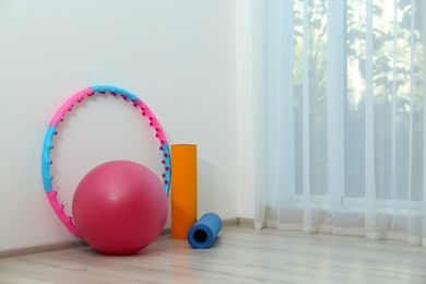 Hula hoop, fitness ball and mats near light wall in gym