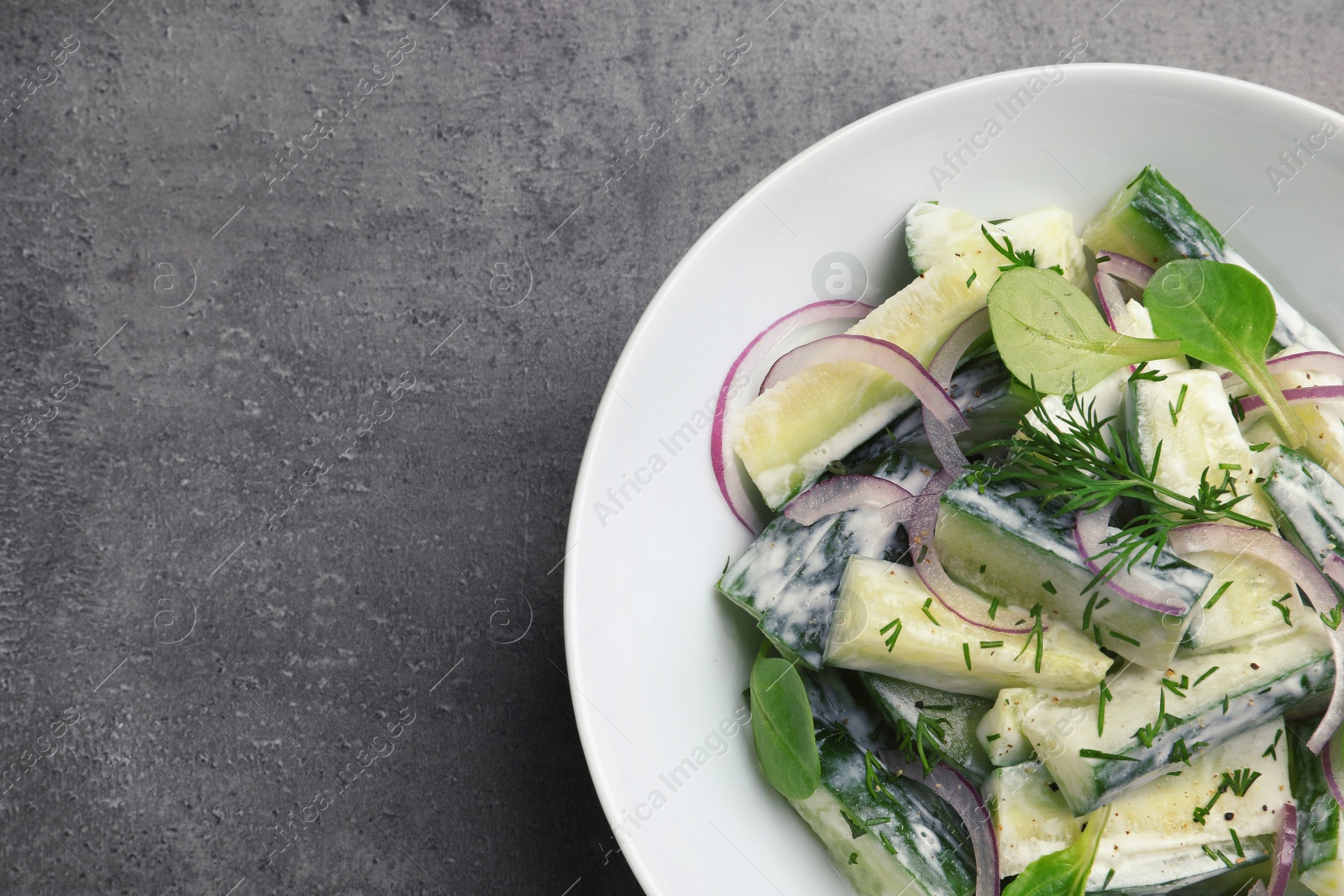 Photo of Plate with creamy cucumber salad on table, top view. Space for text