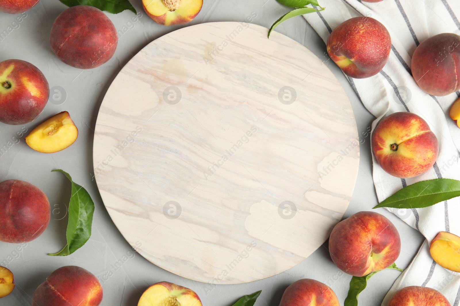 Photo of Flat lay composition of ripe peaches and stone board on grey table, space for text