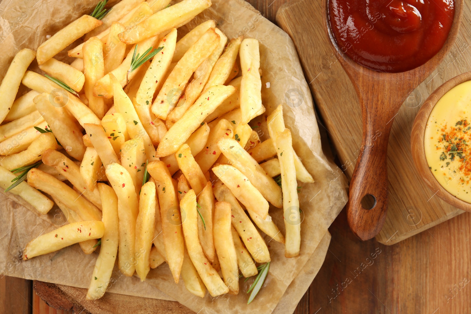 Photo of Delicious french fries served with sauces on wooden table, flat lay