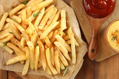Photo of Delicious french fries served with sauces on wooden table, flat lay