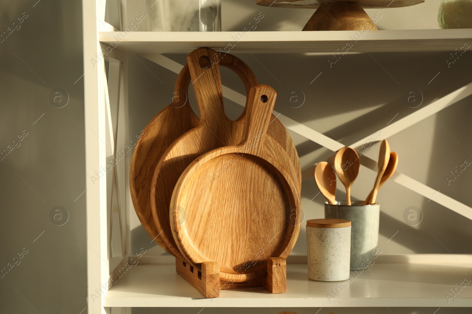 Photo of Wooden cutting boards and kitchen utensils on shelving unit