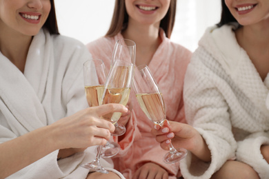 Photo of Young ladies clinking glasses of champagne at pamper party, closeup. Women's Day