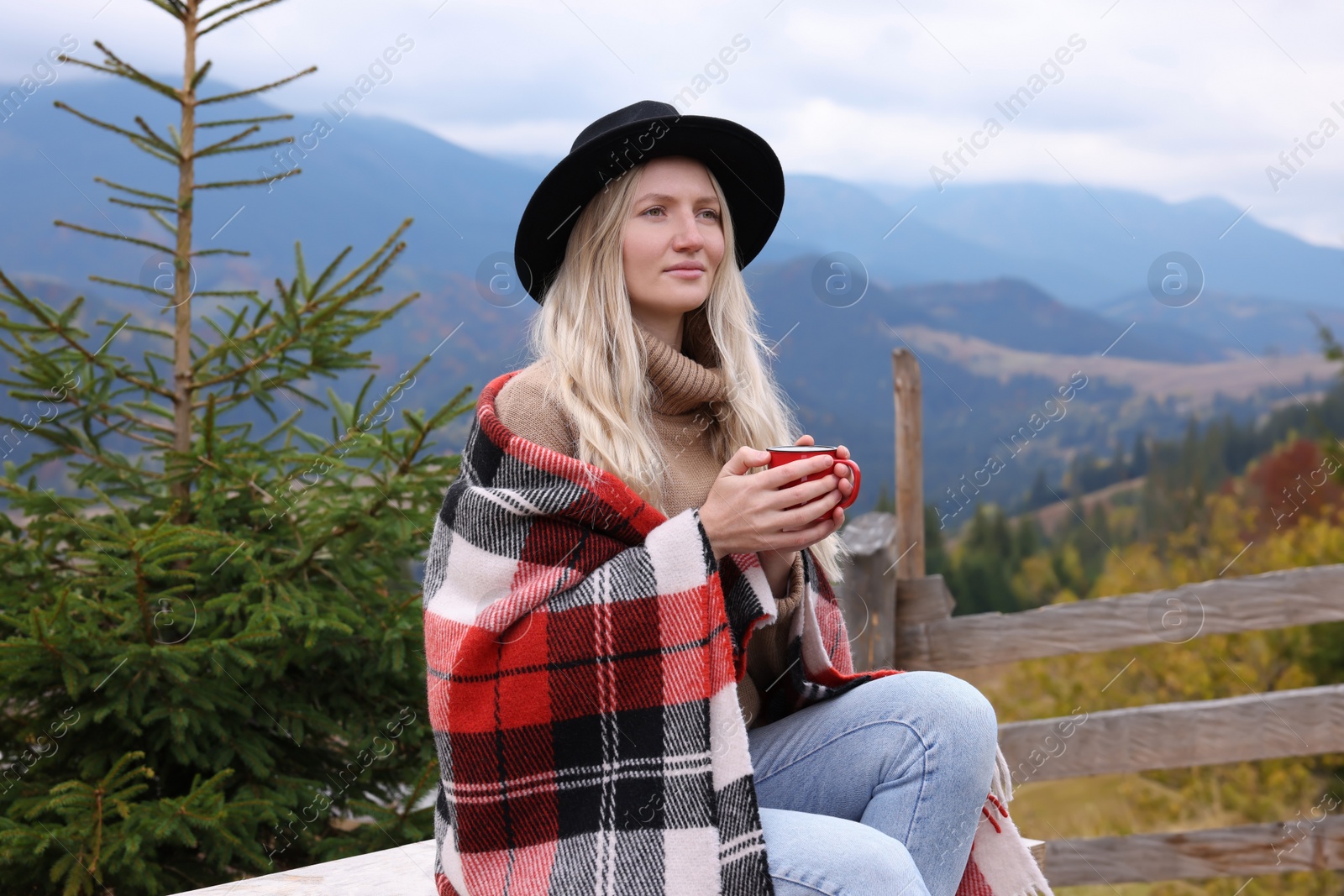 Photo of Young woman with mug of hot drink in mountains