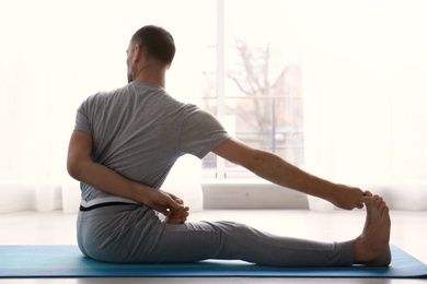 Photo of Sporty man practicing yoga indoors