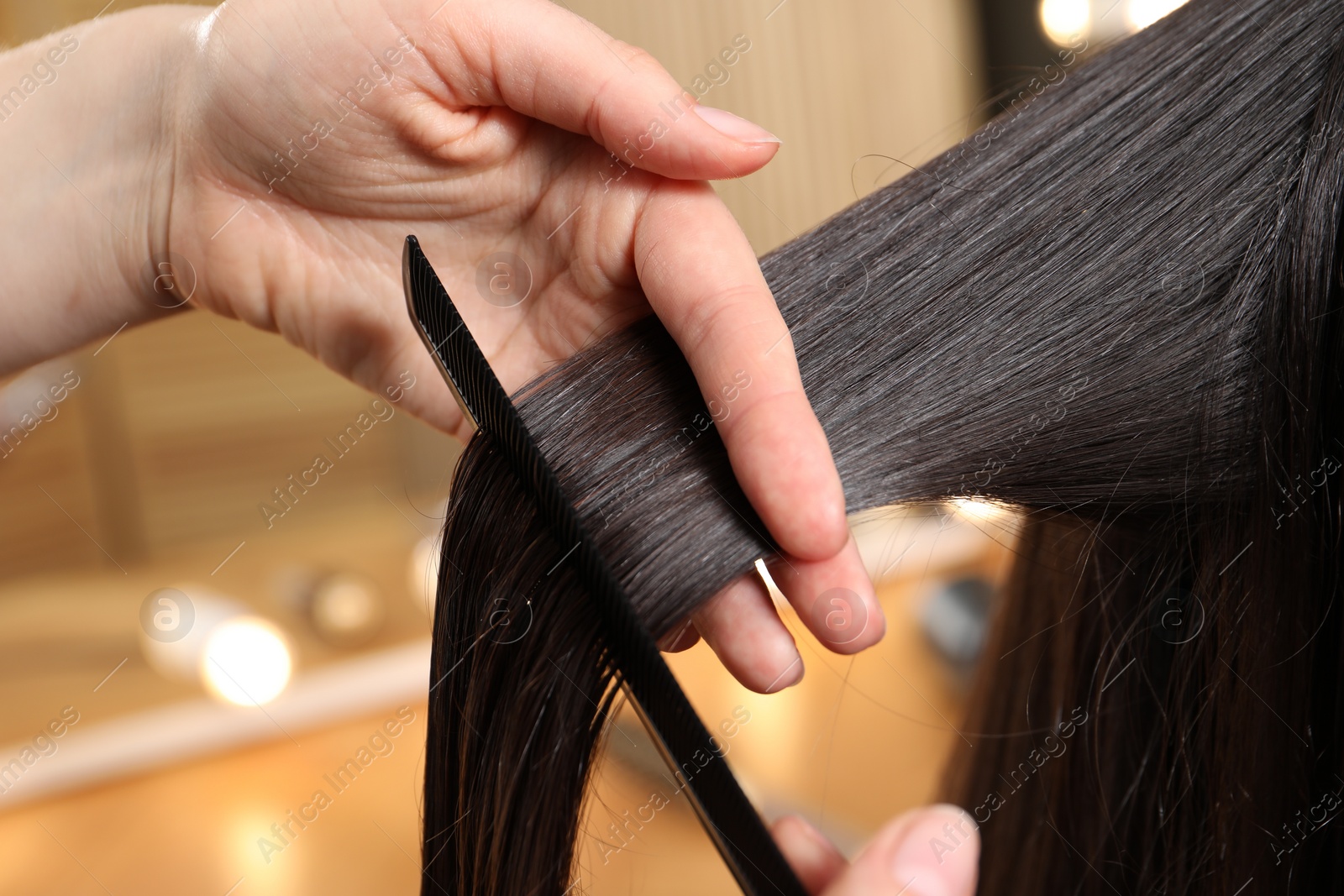 Photo of Hairdresser combing client's hair in salon, closeup