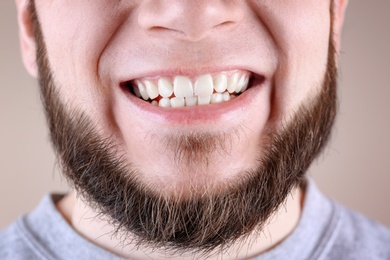 Young man with healthy teeth smiling on color background, closeup