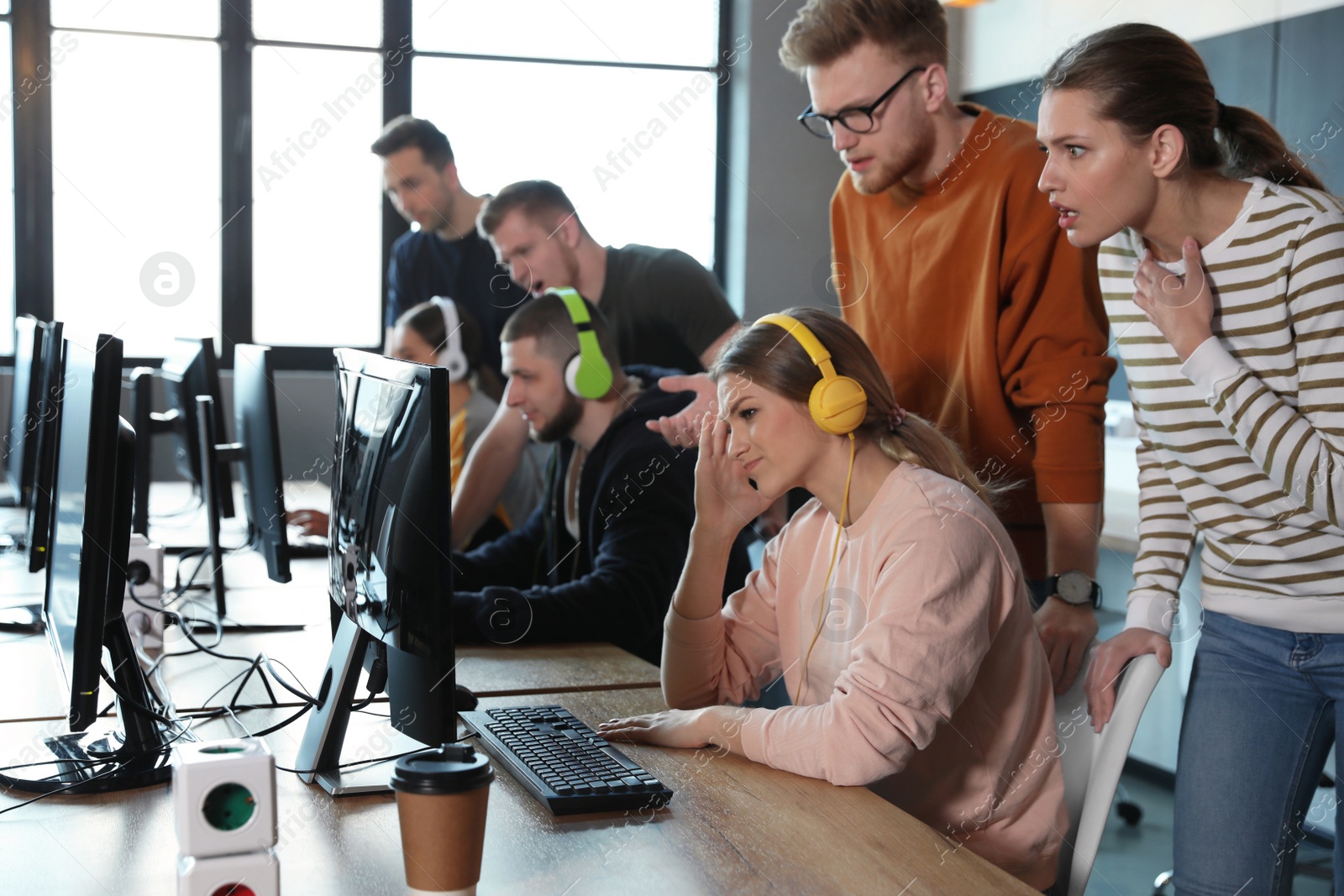 Photo of Group of people playing video games in internet cafe