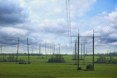 Photo of Telephone poles with cables in field under clear sky