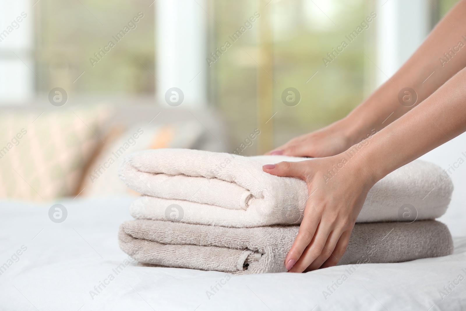 Photo of Woman putting soft clean terry towels onto bed, closeup
