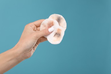 Photo of Woman with dirty cotton pads after removing makeup on light blue background, closeup. Space for text