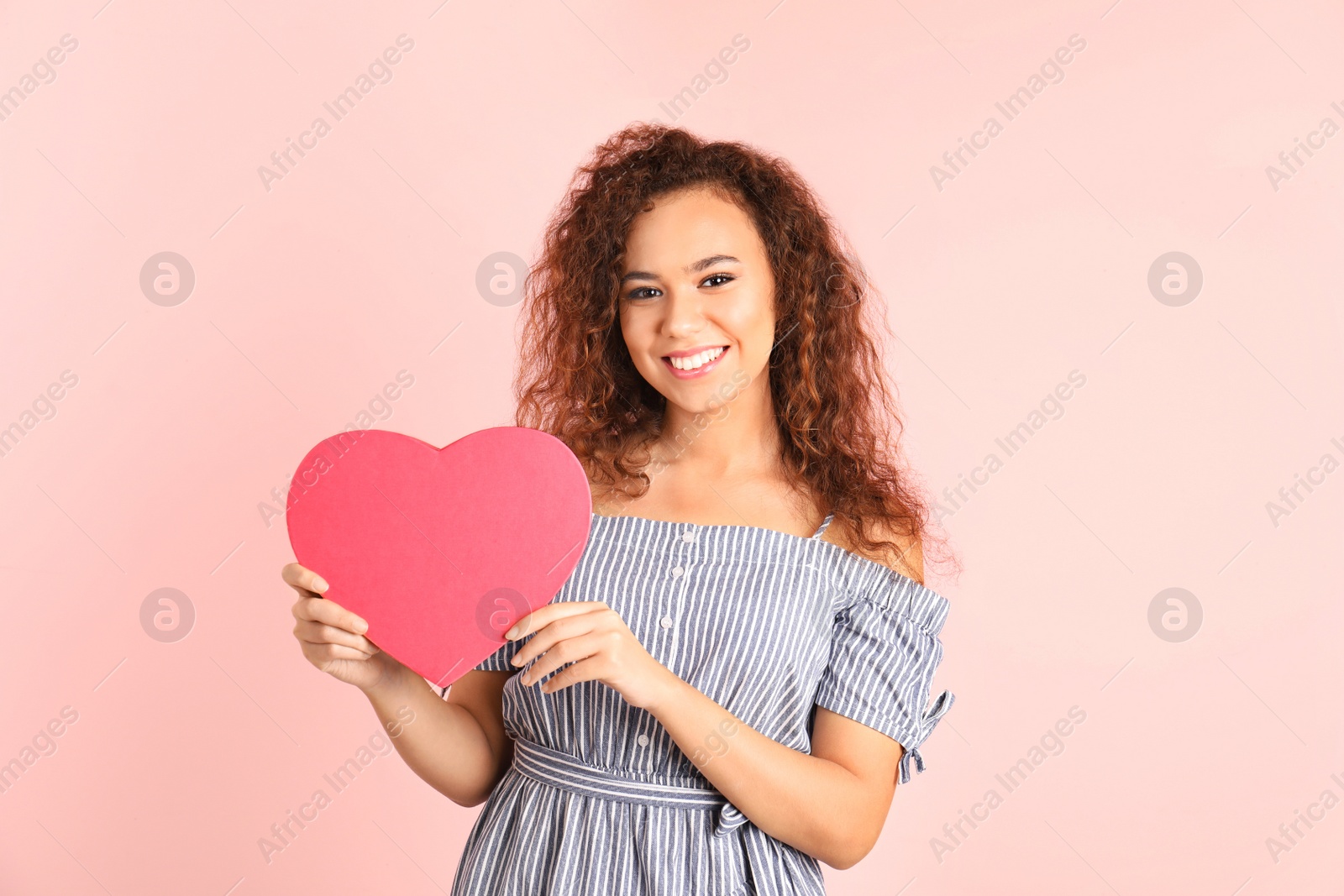 Photo of African-American woman with heart shaped box on color background