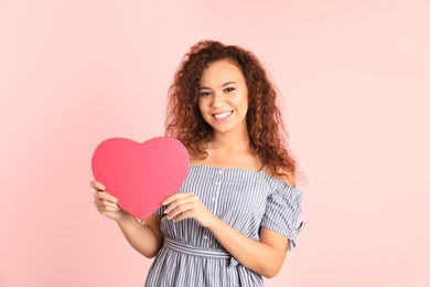 Photo of African-American woman with heart shaped box on color background